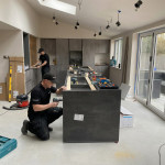 Mastercraft Kitchens installation team assembling a contemporary kitchen island and cabinetry during the fitting of a bespoke fitted kitchen within a modern open plan home.