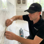 Mastercraft Kitchens installer carefully fitting marble effect wall tiles during the installation of a bespoke fitted kitchen, demonstrating the craftsmanship and attention to detail involved in every Mastercraft project.
