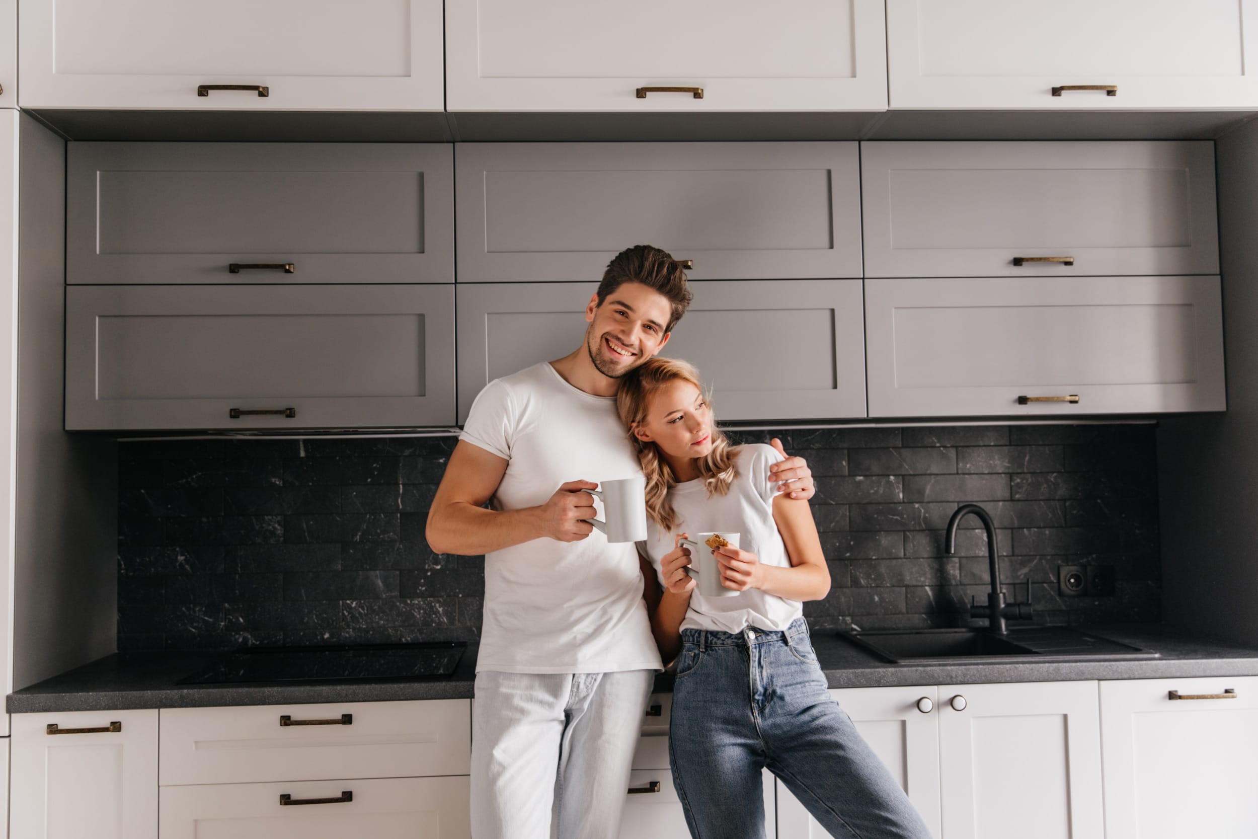 A young couple enjoying their new bespoke kitchen and drinking a coffee