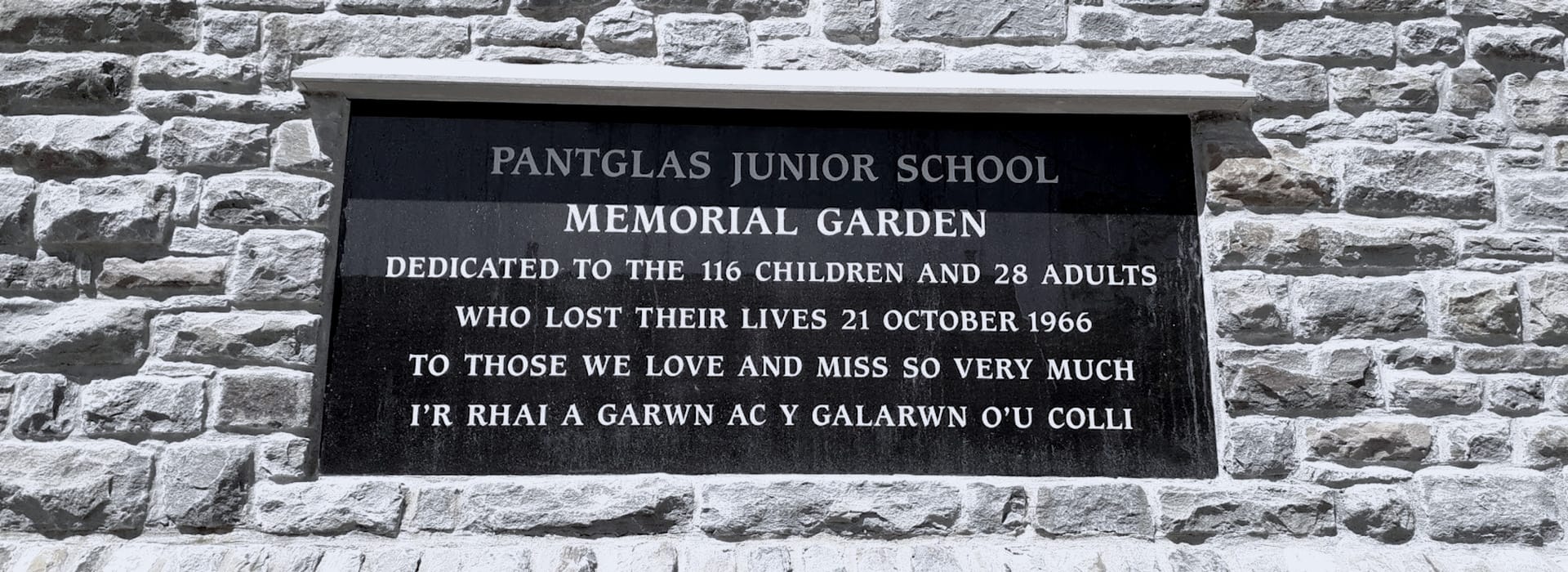 Black stone plaque with white engraved text on a grey brick wall