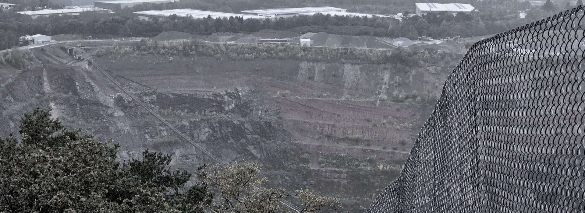 grey industrial quarry landscape with chain link fence on the right