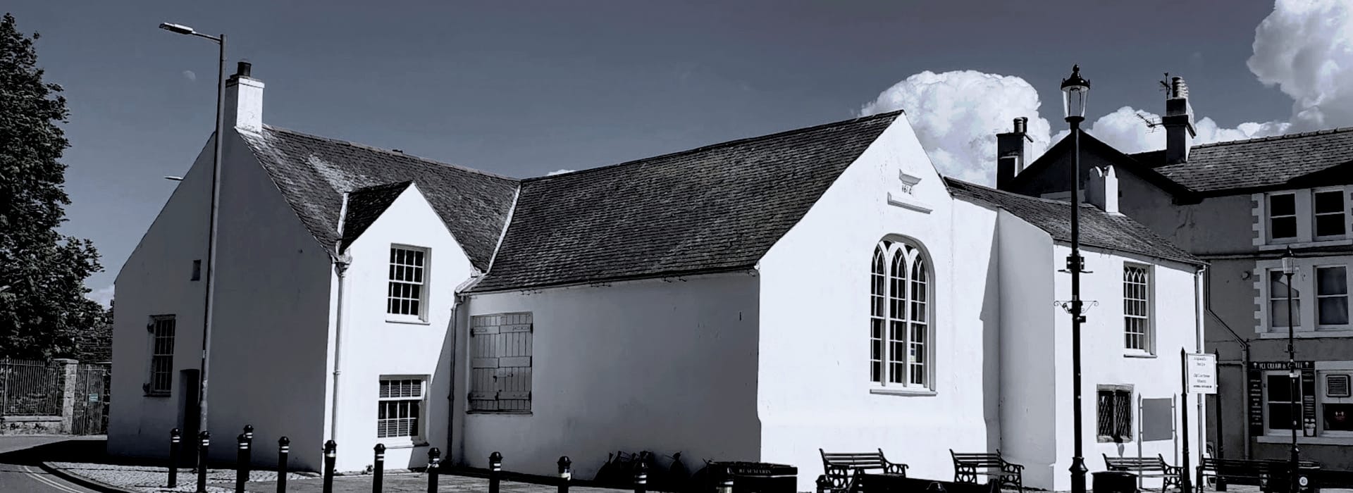 Bespoke Kitchens Beaumaris - Mastercraft Kitchens whitewashed building with steep slate roof and arched window under cloudy sky