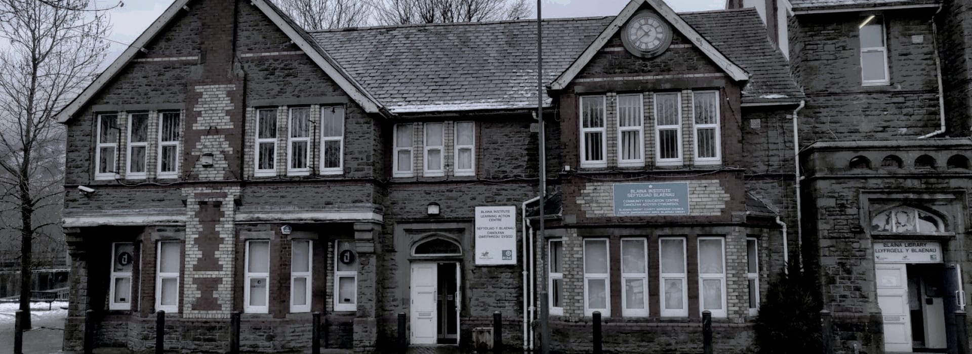 Victorian stone building with patterned brickwork and a central clock above windows