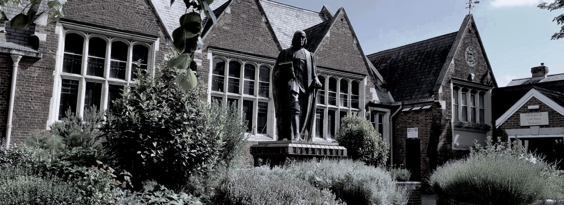 Bespoke Kitchens Braintree - Mastercraft Kitchens bronze statue in front of red brick building with arched windows and gabled roof