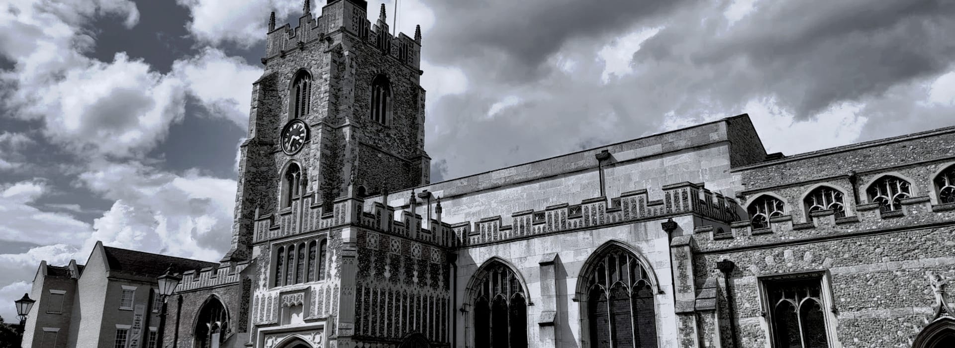 stone church with tall clock tower under dramatic cloudy sky