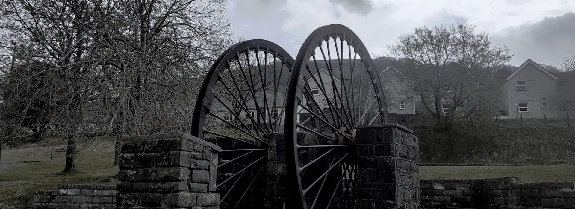 Bespoke Kitchens Abertillery - Mastercraft Kitchens two large metal wheels set in stone structure with houses in background