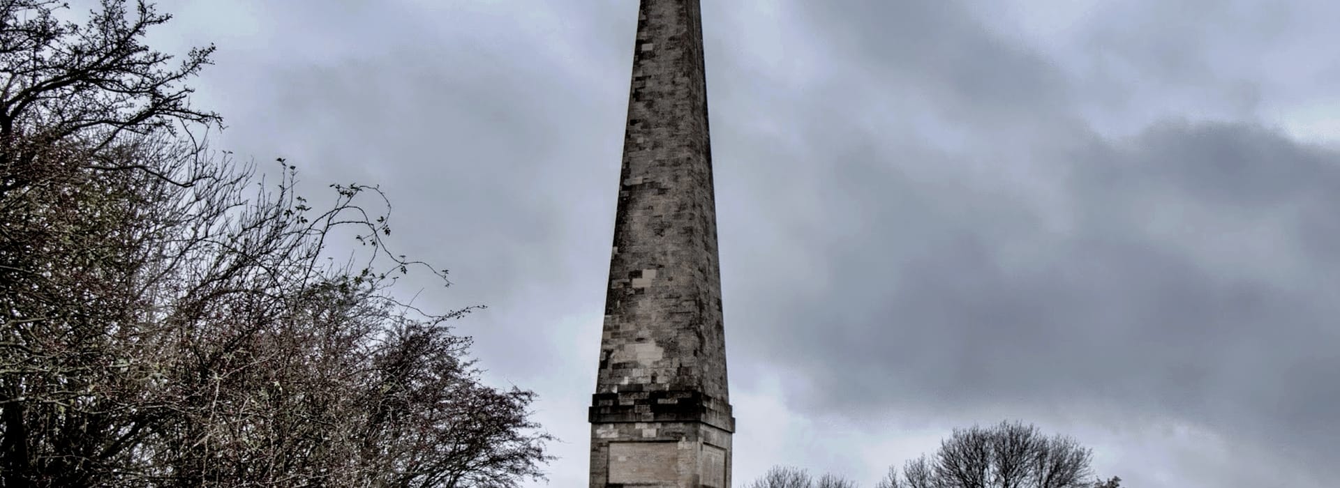 Bespoke Kitchens Ledbury - Mastercraft Kitchens tall stone obelisk against overcast grey sky with bare trees