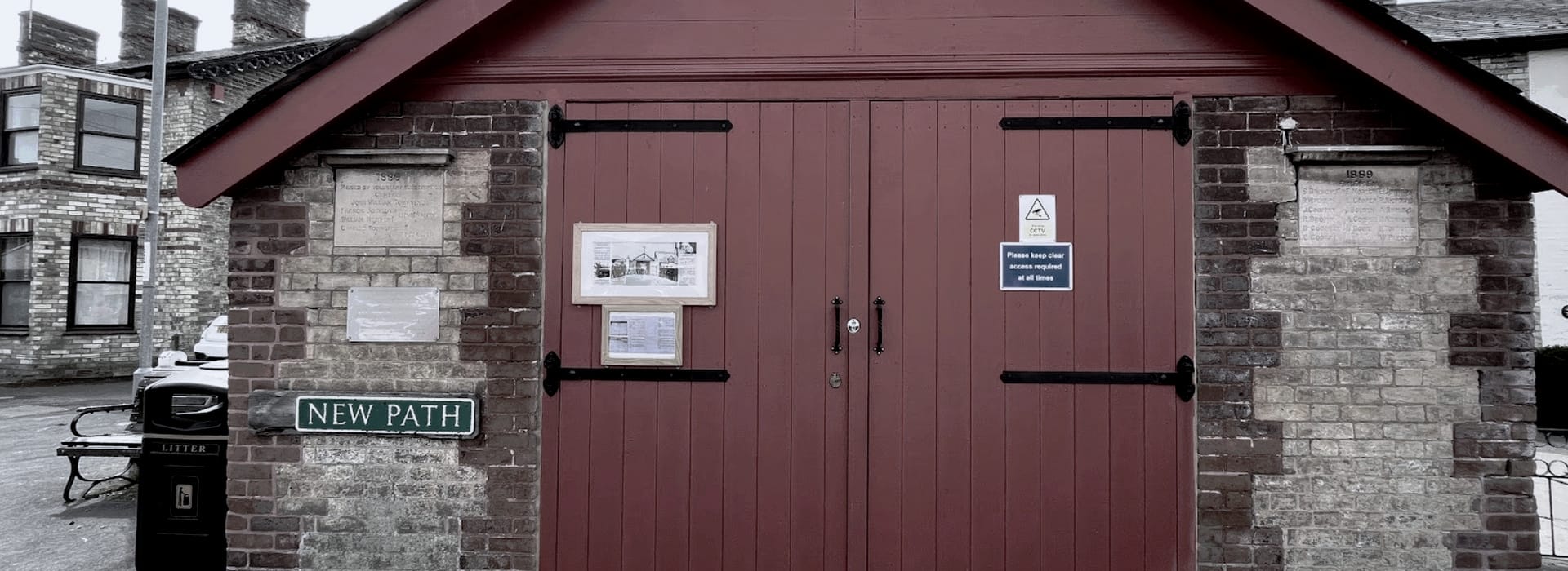 Red wooden double doors with black hinges and brickwork surround