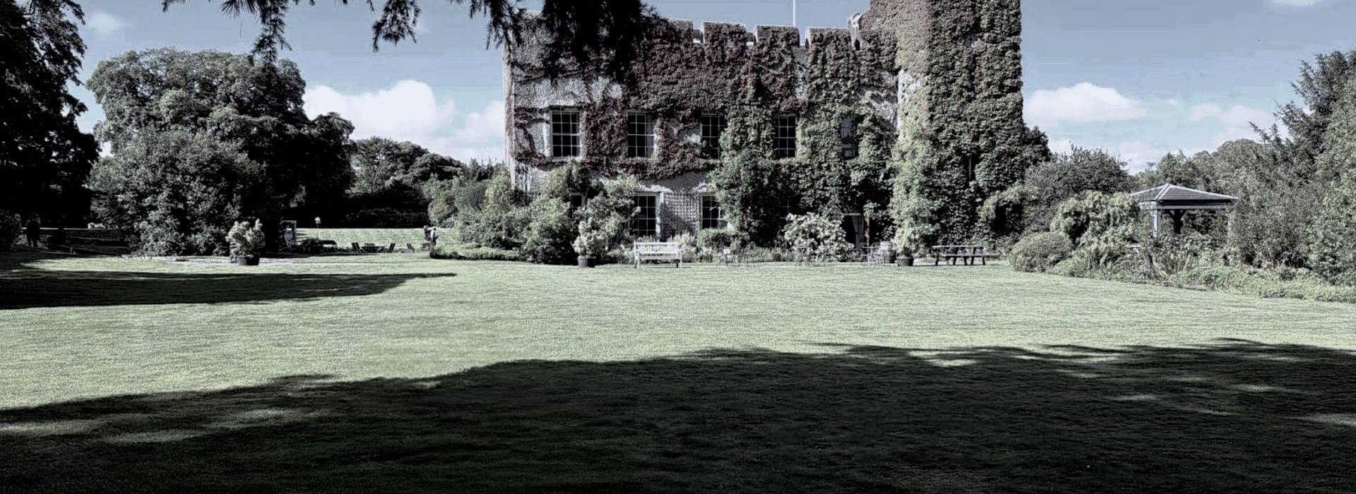 historic stone building with ivy-covered walls and large manicured lawn