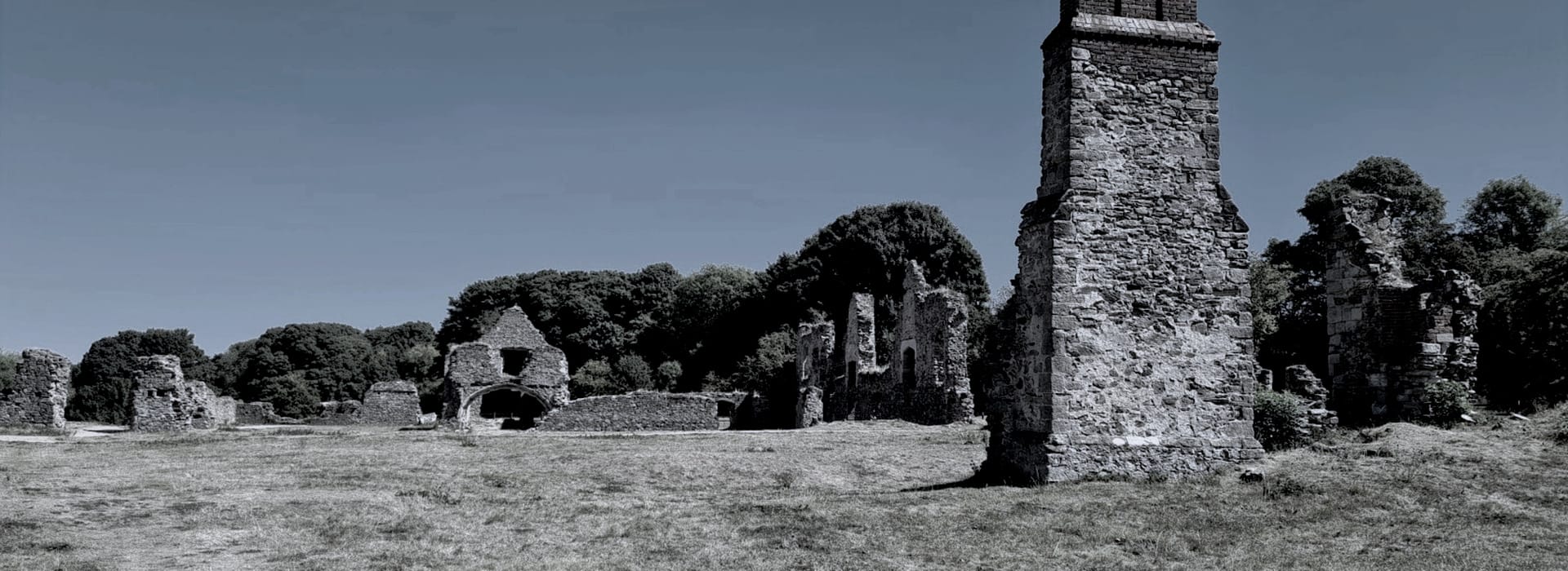 ancient stone ruins scattered across grassy field under clear blue sky