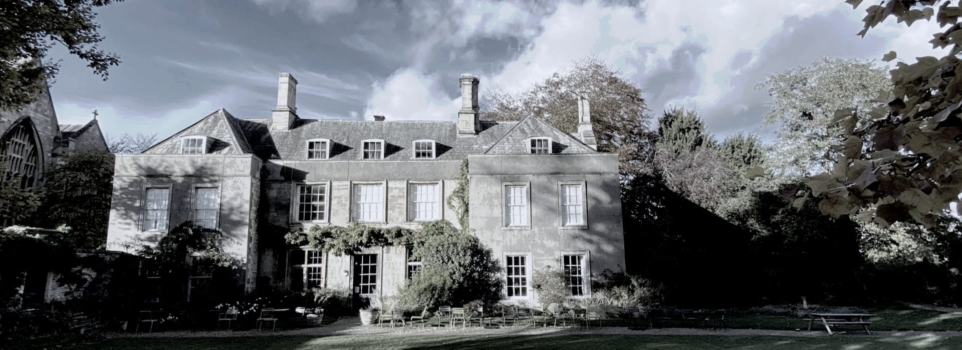 grey stone manor house with tall chimneys and climbing greenery