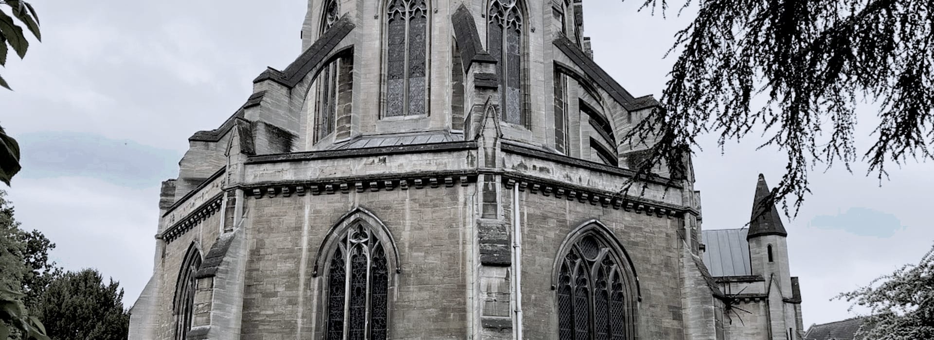 grey stone church with pointed arched windows and gothic architectural details