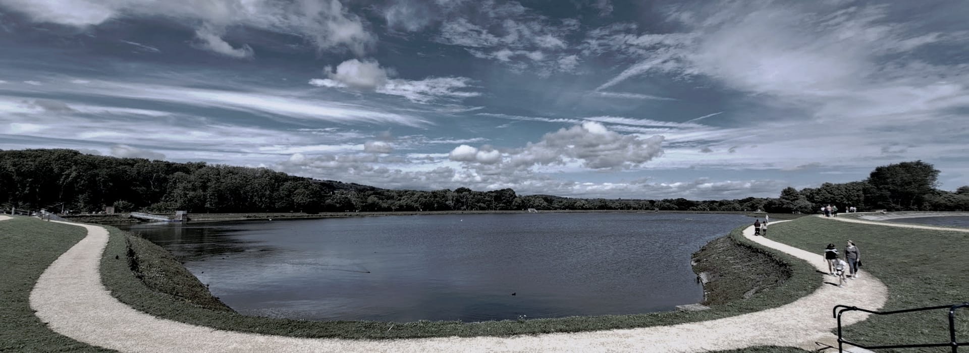 curved gravel path around a large lake under dramatic cloudy sky