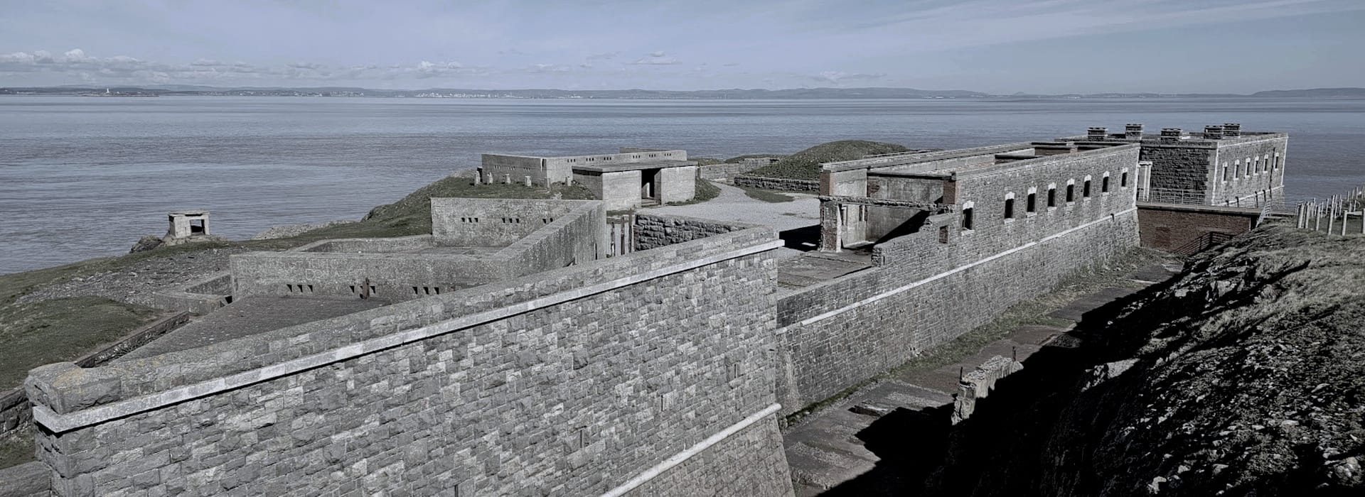 large stone fortress with rectangular towers overlooking calm blue sea