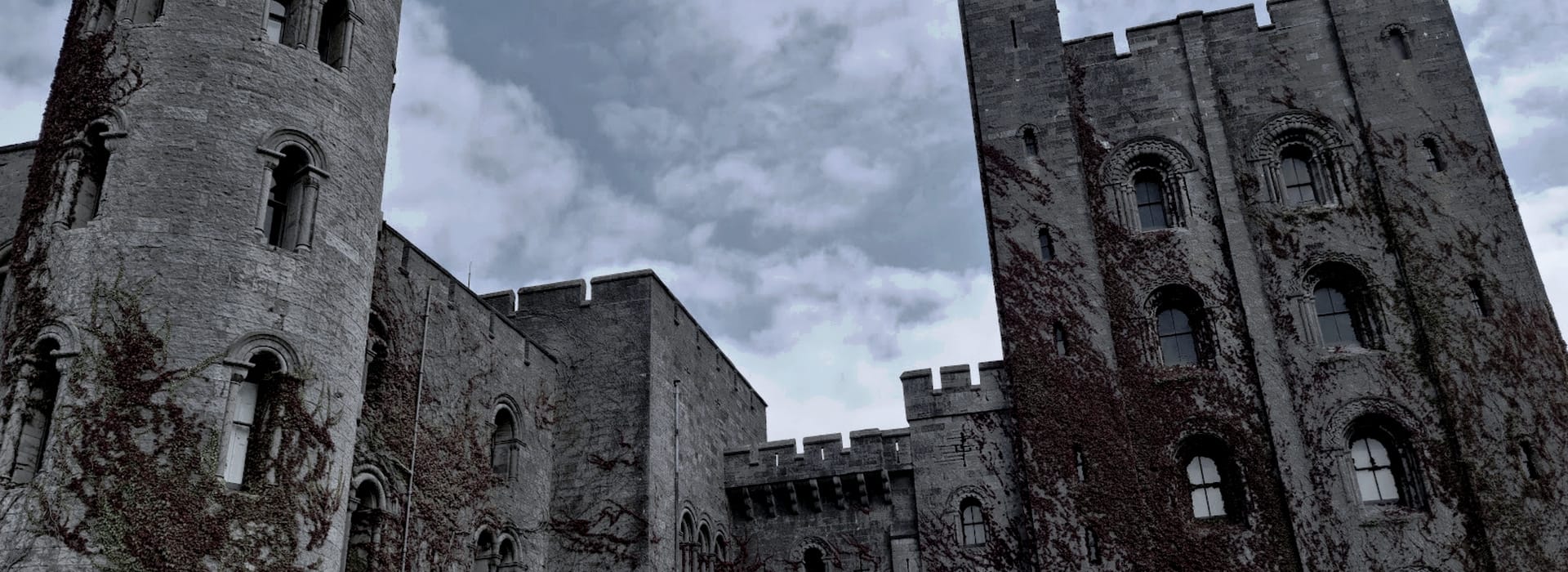 grey stone castle towers with arched windows and creeping ivy