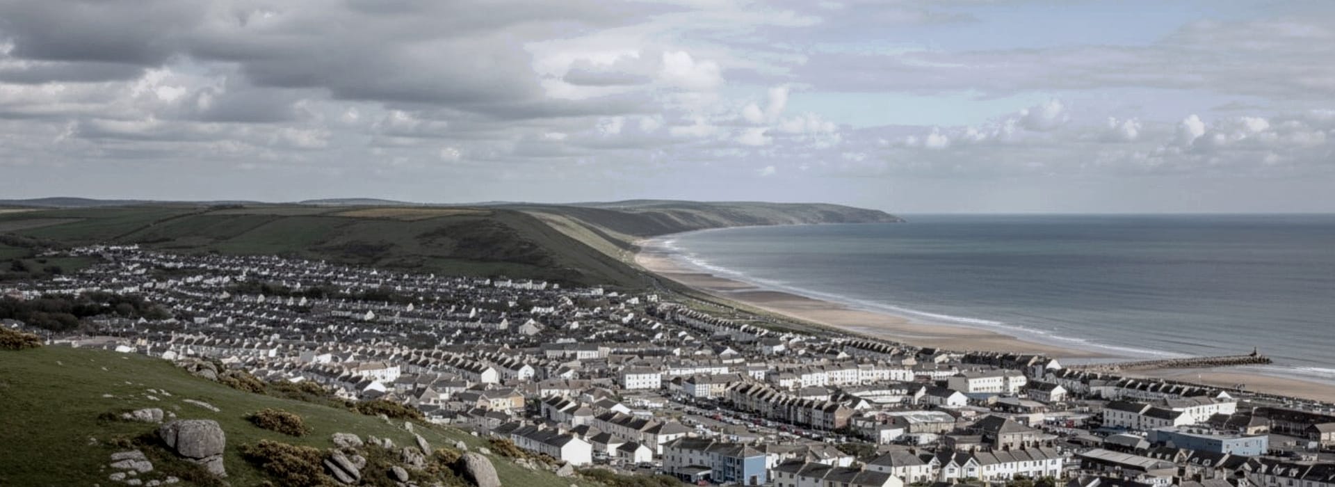 Bespoke Kitchens Bryn Newydd - Mastercraft Kitchens coastal town with rows of houses, sandy beach and rolling green hills