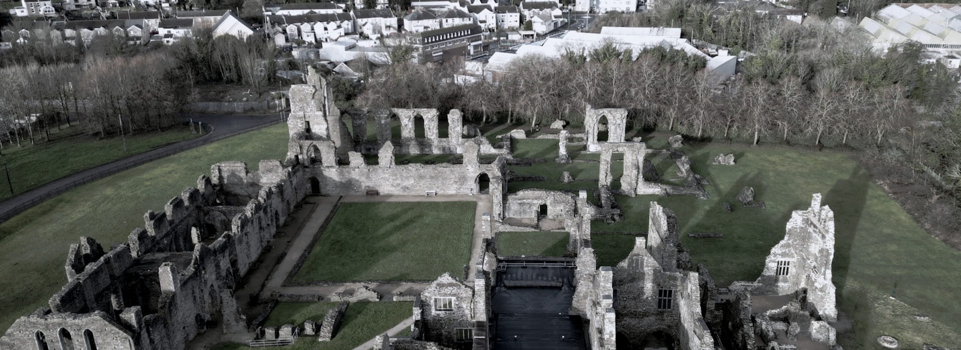 stone ruins with rectangular grass courtyard and surrounding trees