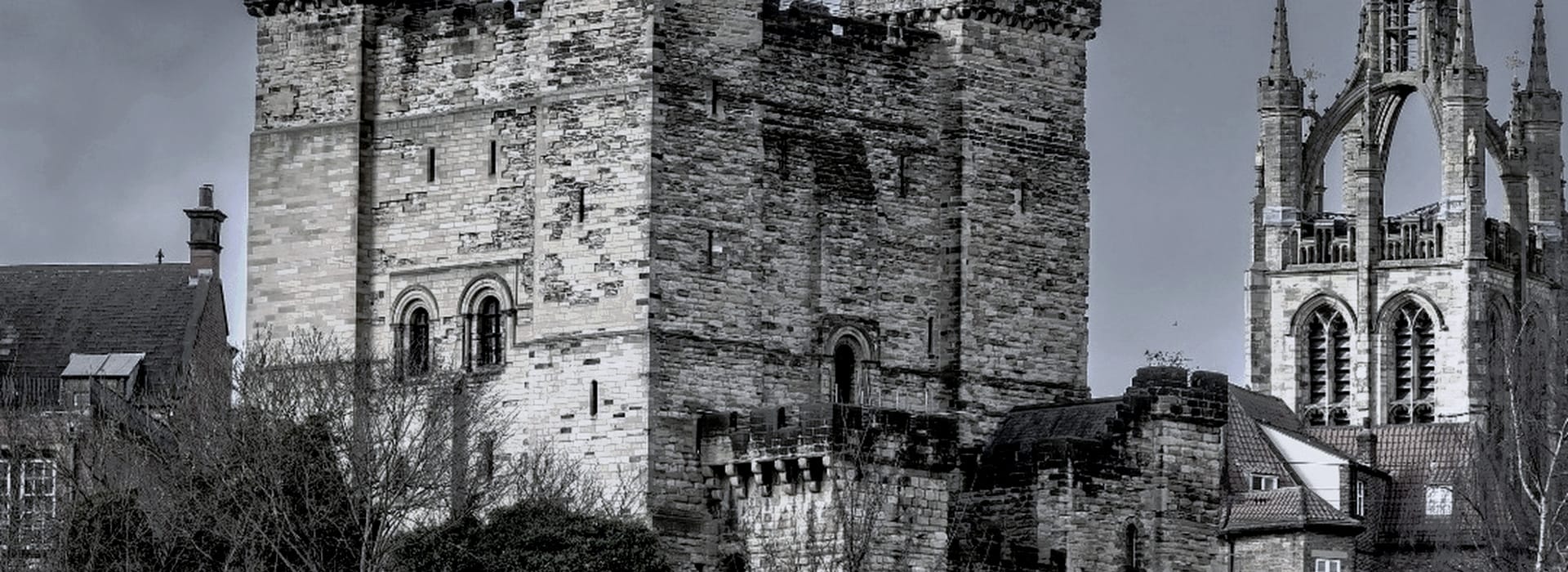 medieval stone castle with square tower beside gothic church spire