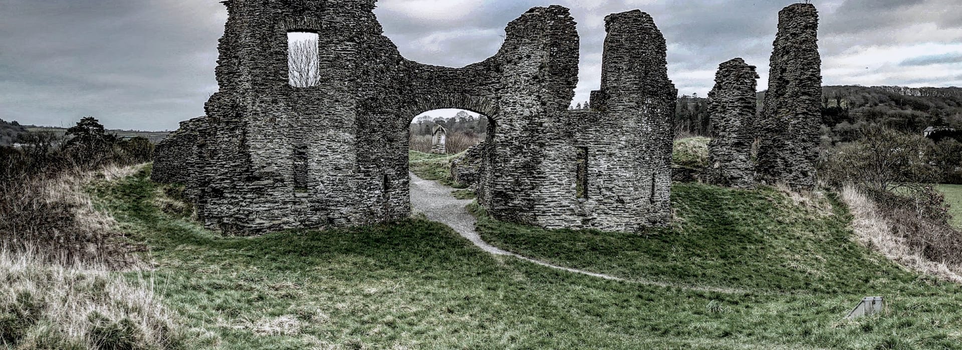 weathered stone castle ruins with arched entrance on grassy hill