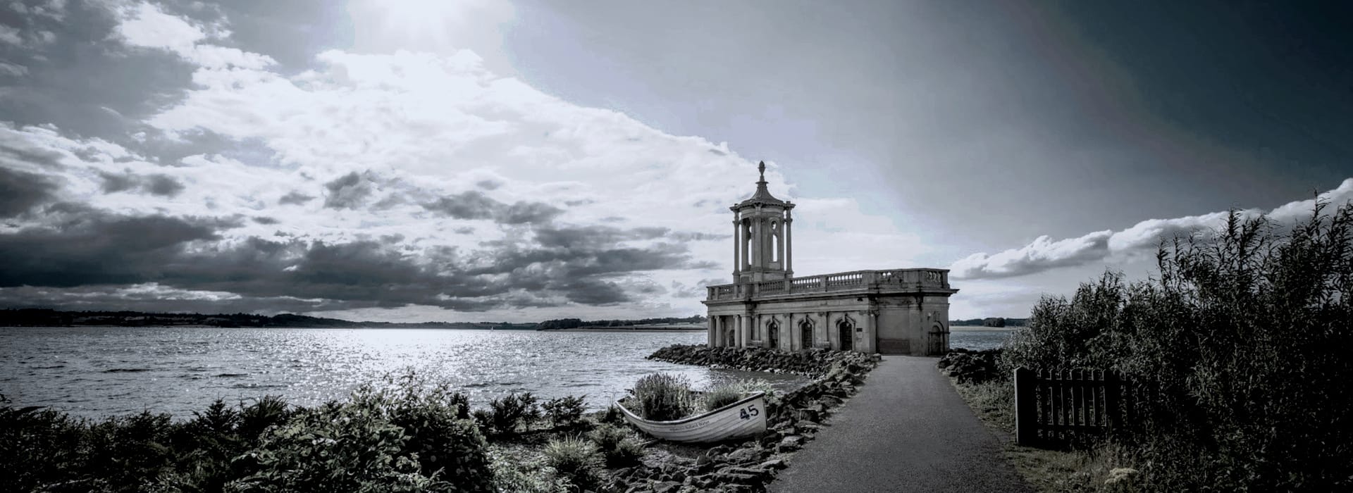 Bespoke Kitchens Oakham - Mastercraft Kitchens moody lakeside scene with stone church and dramatic cloudy sky