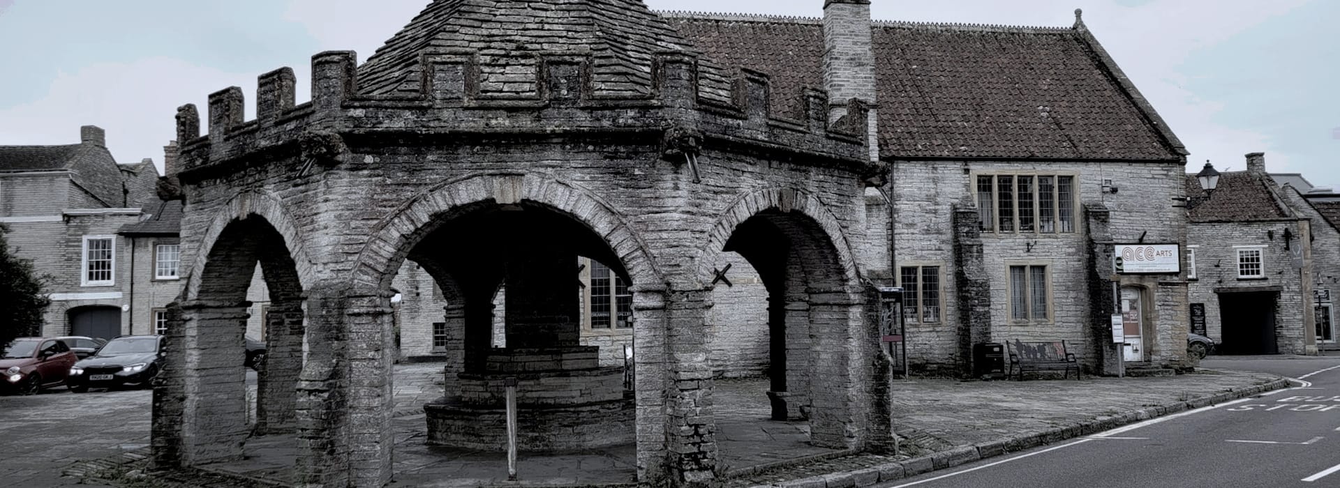 stone market cross with arched openings in a grey historic town square