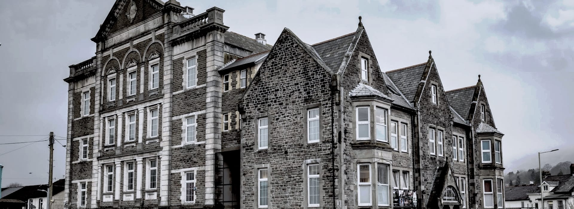 Victorian stone building with gabled roofs and white-trimmed sash windows