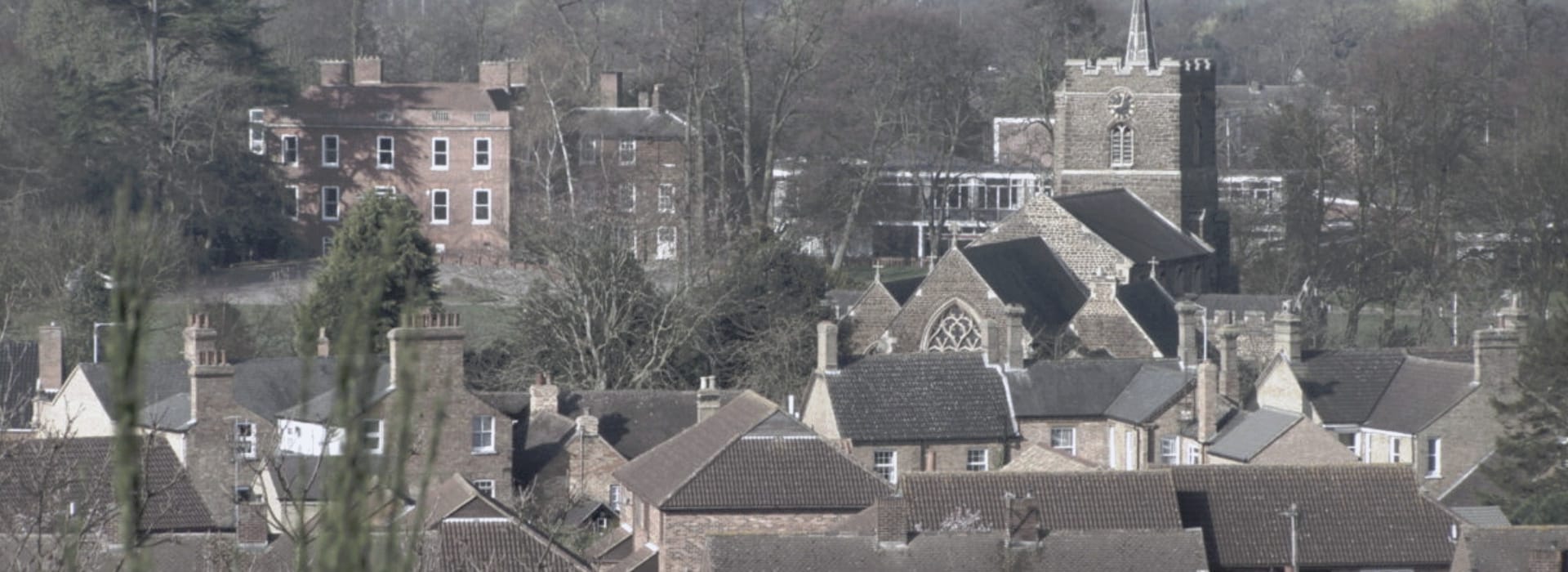 Muted village rooftops with a stone church and arched window centre