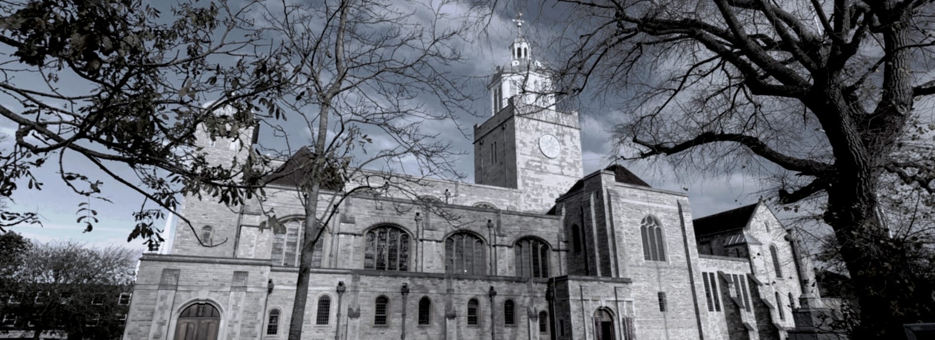 stone church with tall clock tower framed by bare tree branches