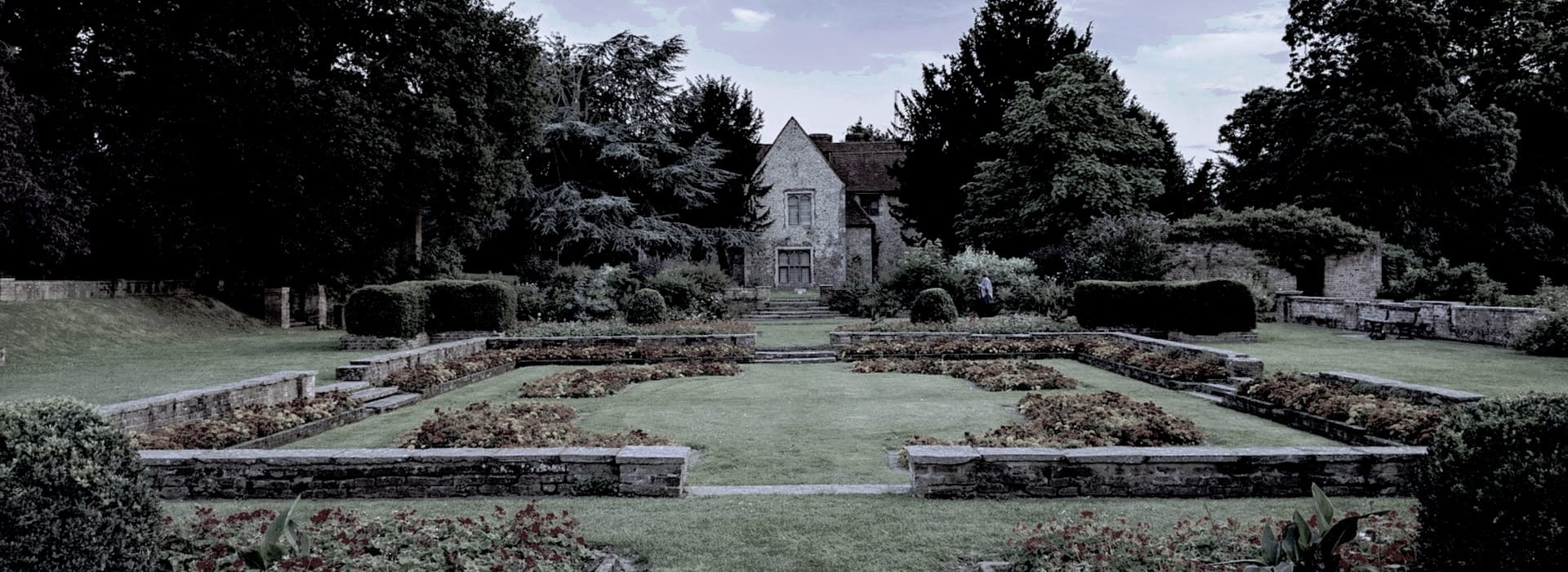 historic stone house with symmetrical formal gardens and mature trees
