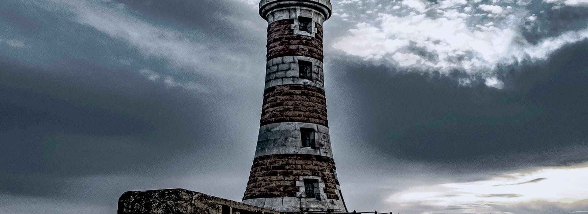Bespoke Kitchens Sunderland - Mastercraft Kitchens striped stone lighthouse against a dramatic cloudy sky