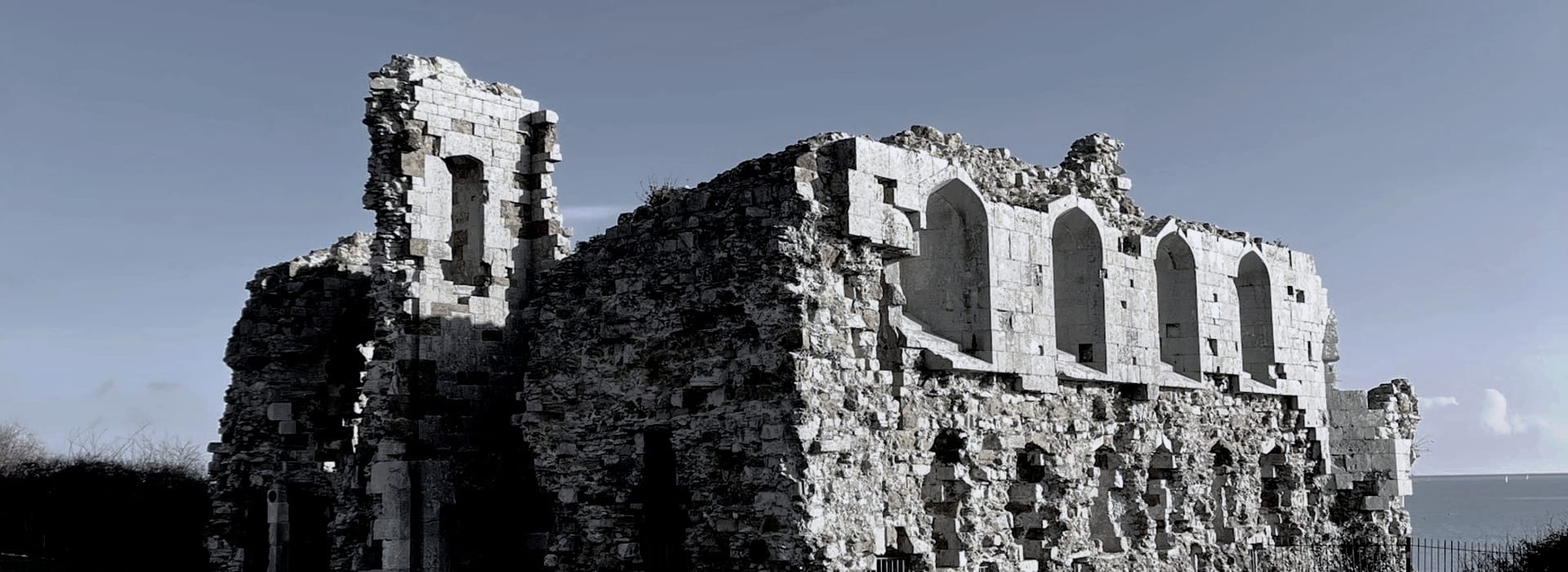 weathered stone ruin with arched windows against a pale blue sky