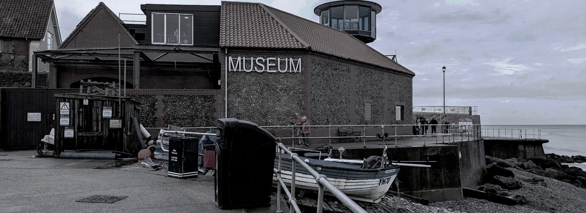 stone museum building with round glass observation tower and beached fishing boat