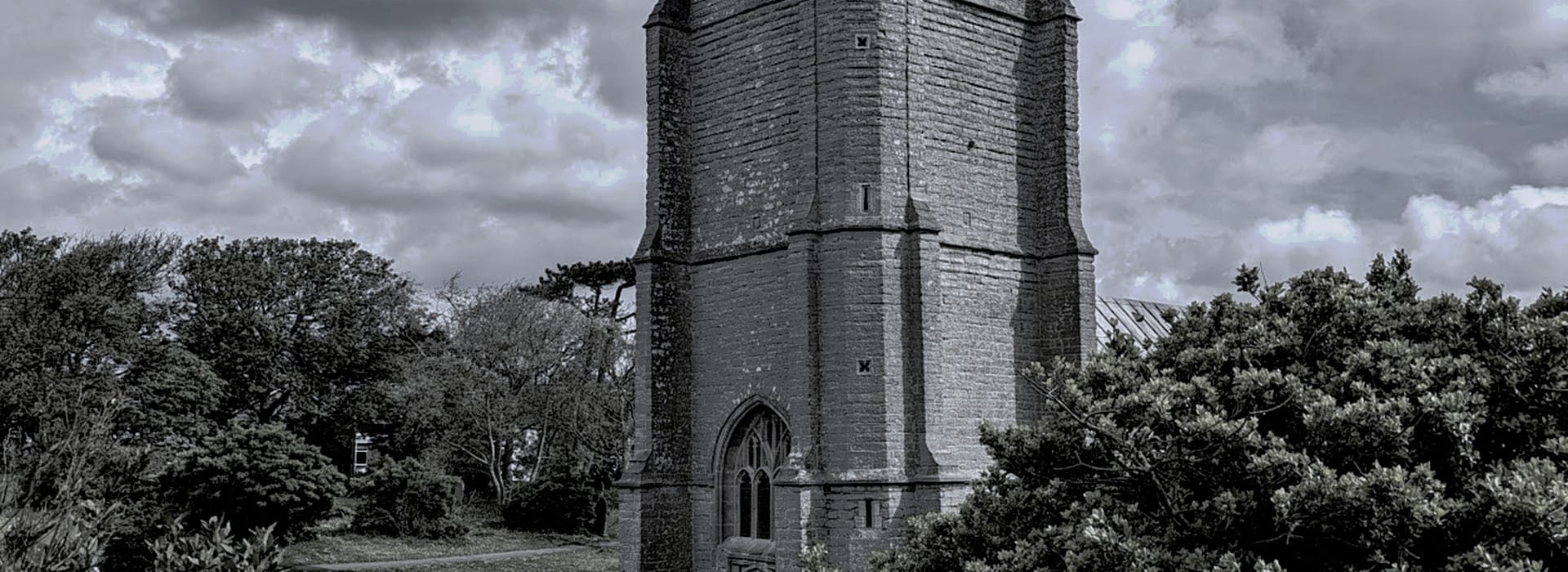 Bespoke Kitchens Burnham-on-Sea - Mastercraft Kitchens grey stone church tower with arched window, surrounded by trees