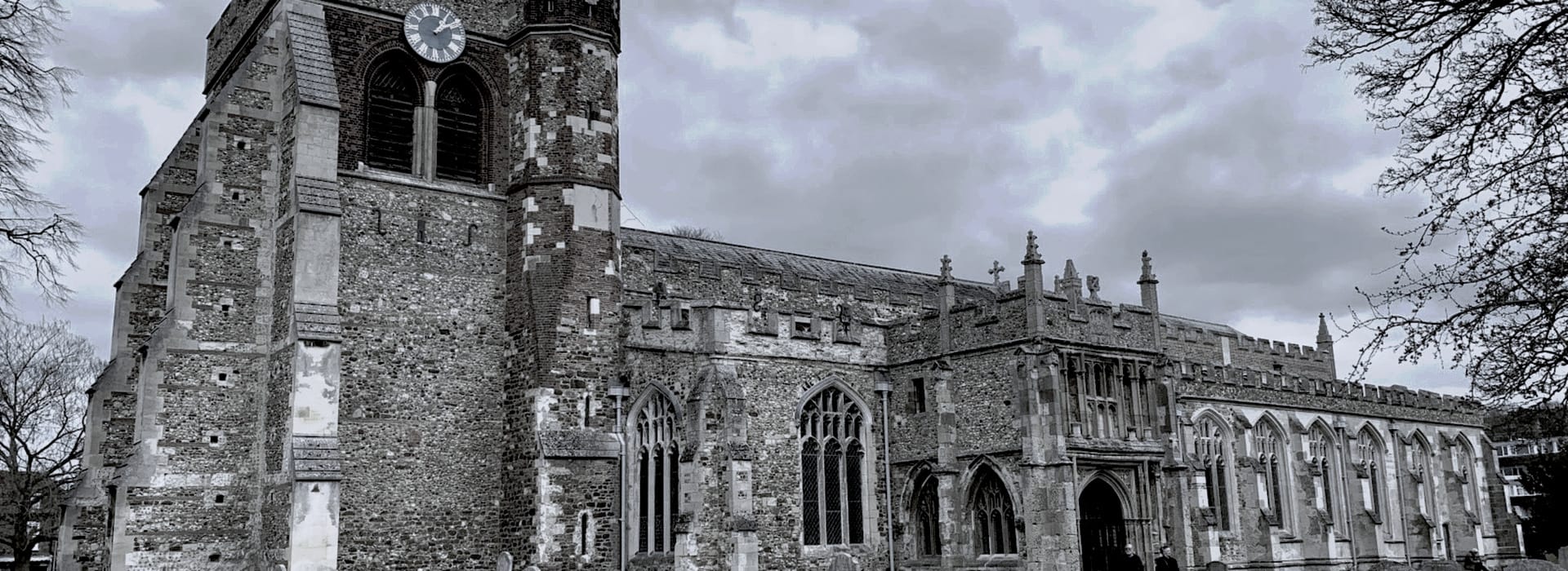 stone church with tall clock tower and arched gothic windows