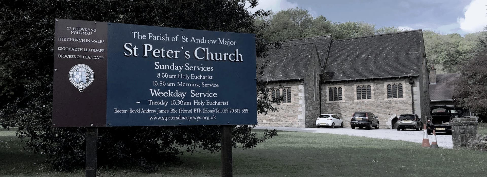 Bespoke Kitchens Dinas Powys - Mastercraft Kitchens Large blue church sign with white text beside stone building and parked cars
