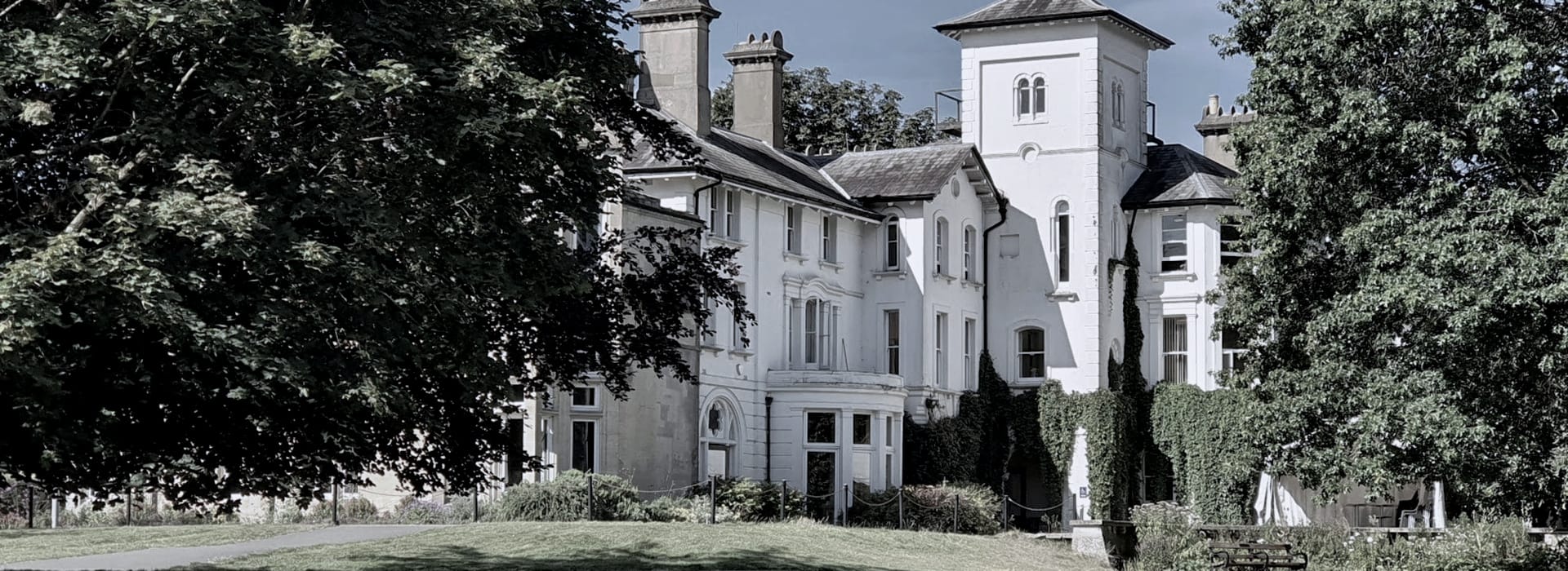Victorian white manor house with central tower and ivy climbing the walls