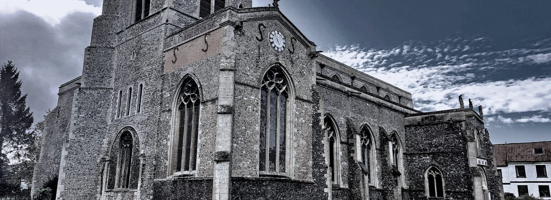 Bespoke Kitchens Attleborough - Mastercraft Kitchens Gothic stone church with arched windows and a clock tower against dramatic sky