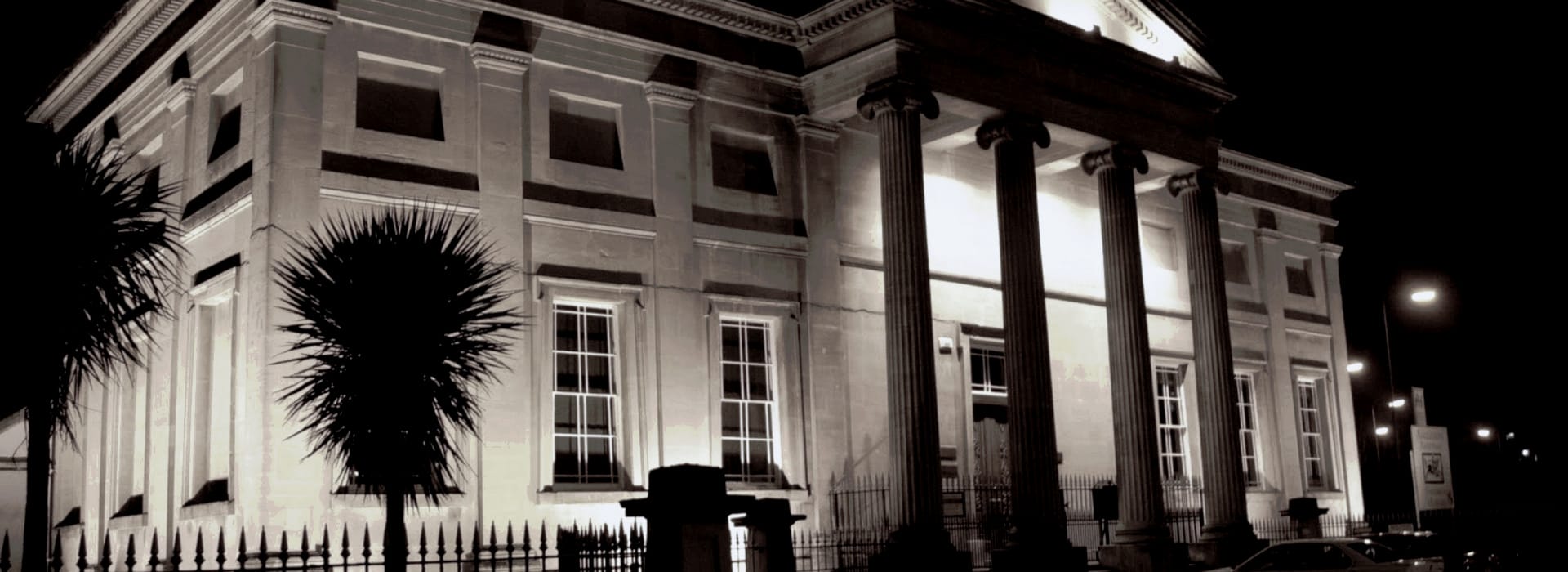 Bespoke Kitchens Swansea - Mastercraft Kitchens grand neoclassical building with tall columns illuminated at night