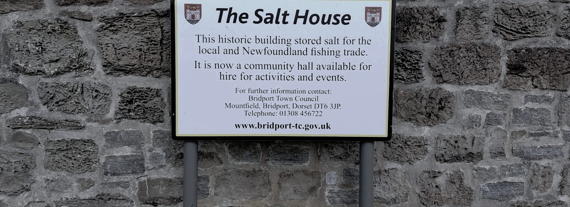 White information sign with black text on a rough grey stone wall