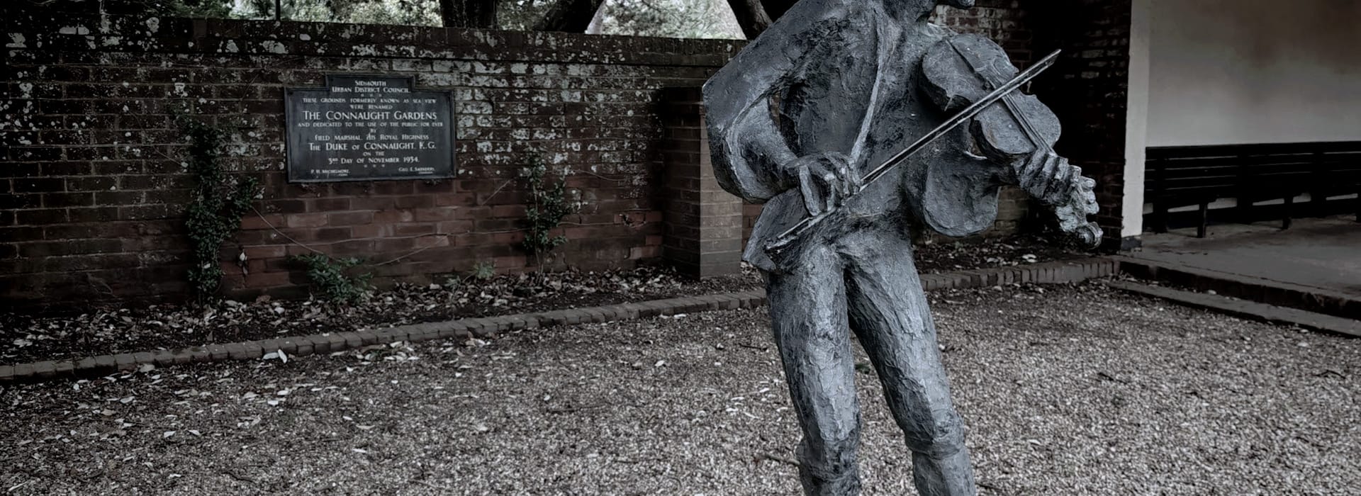 Bespoke Kitchens Sidmouth - Mastercraft Kitchens Weathered bronze statue of violinist in front of mossy brick wall