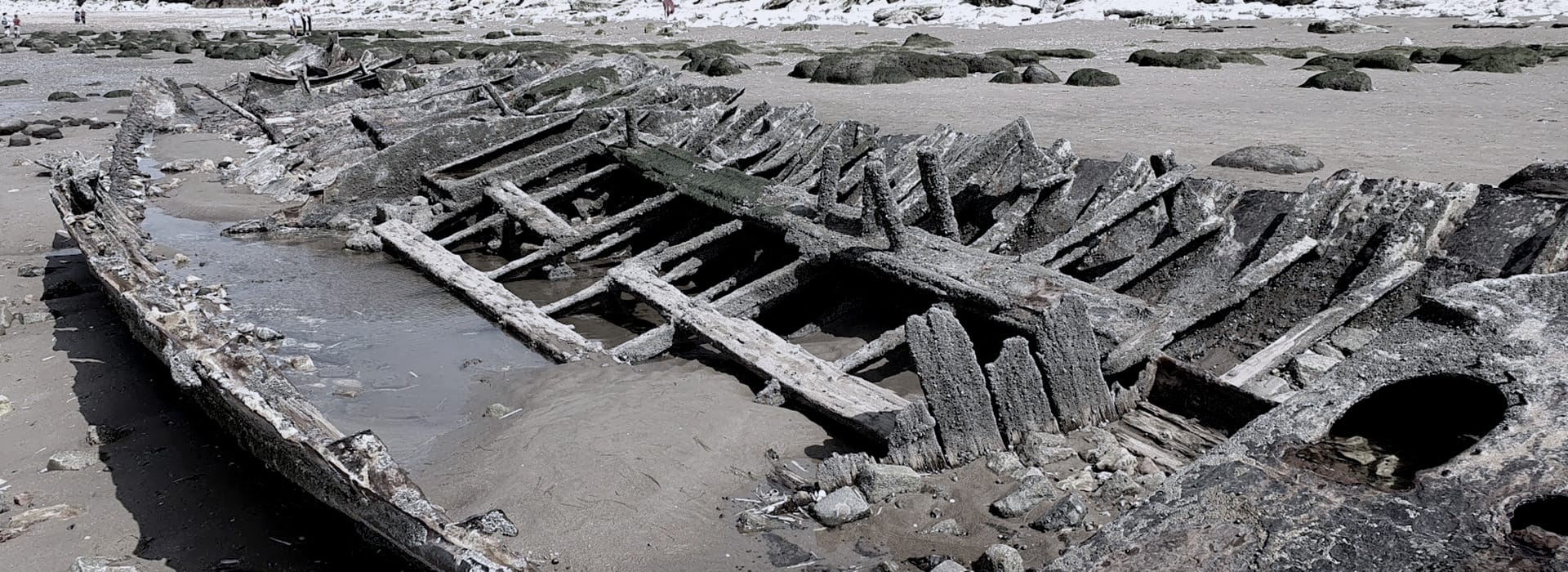 weathered shipwreck with exposed wooden beams on sandy beach
