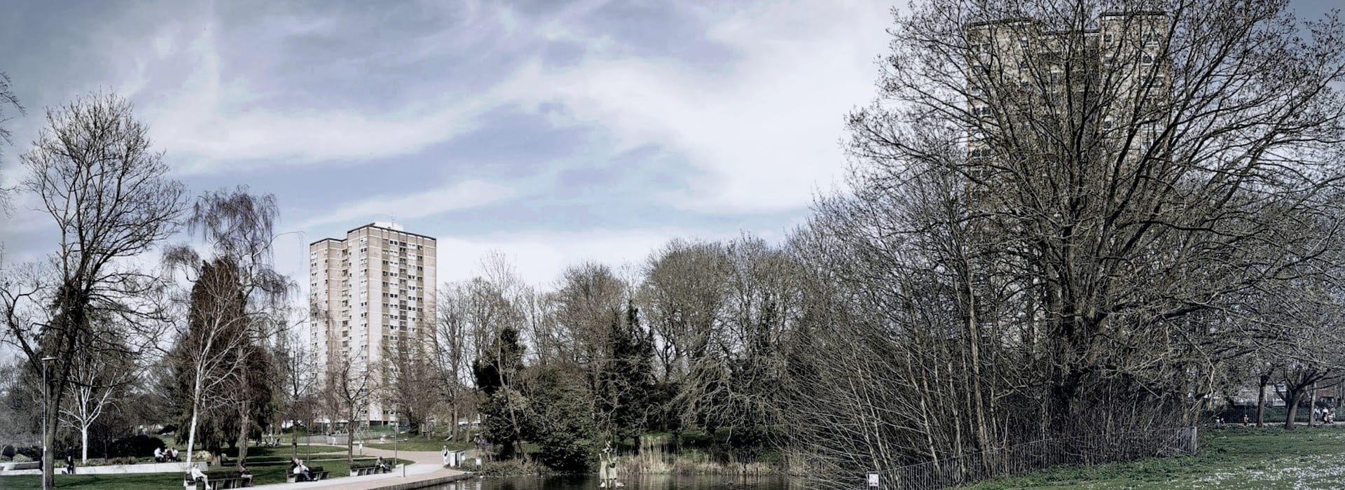 Bespoke Kitchens Stevenage - Mastercraft Kitchens tall beige tower blocks behind leafless trees and a small pond in a park