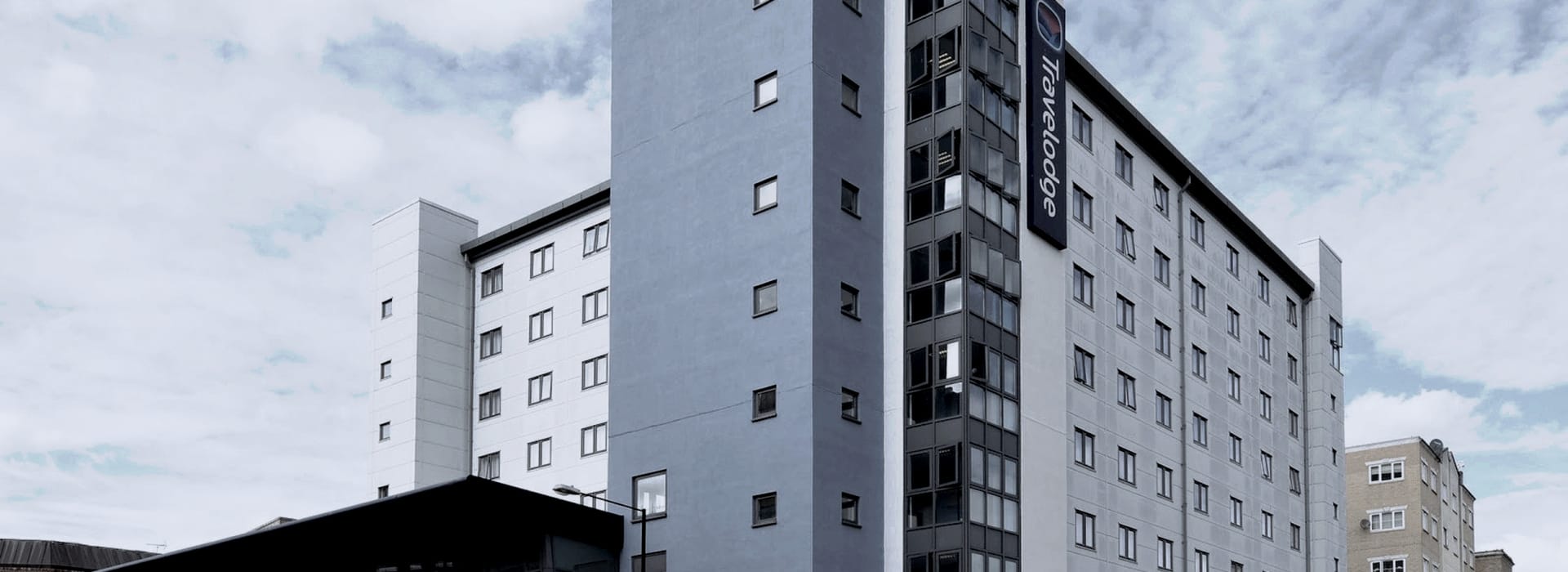 modern grey and white hotel building with rectangular windows and vertical glass stairwell