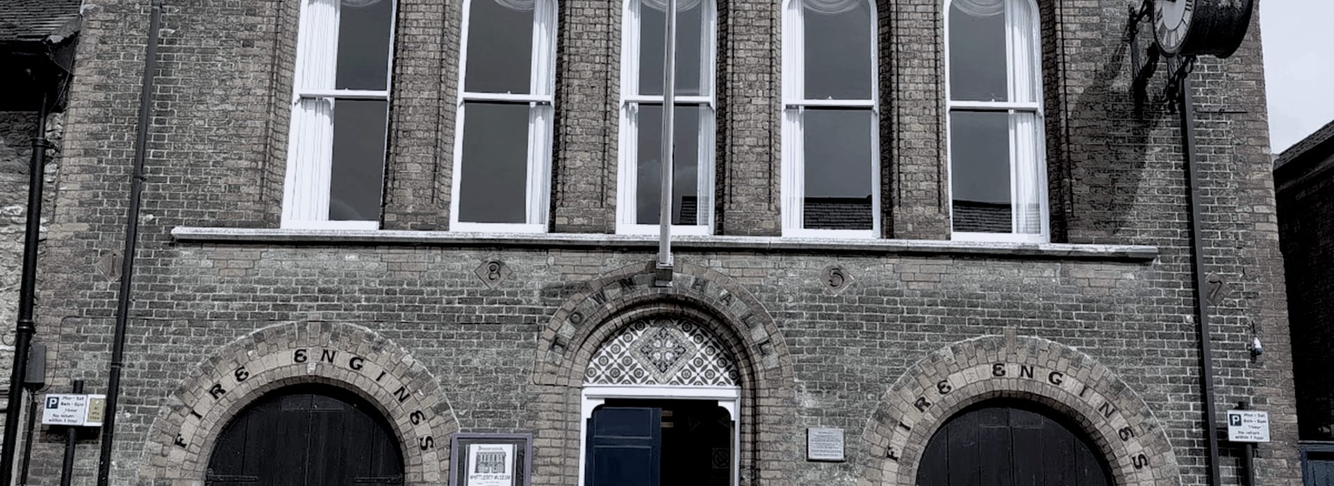 Victorian brick building with arched doorways and large white-framed windows
