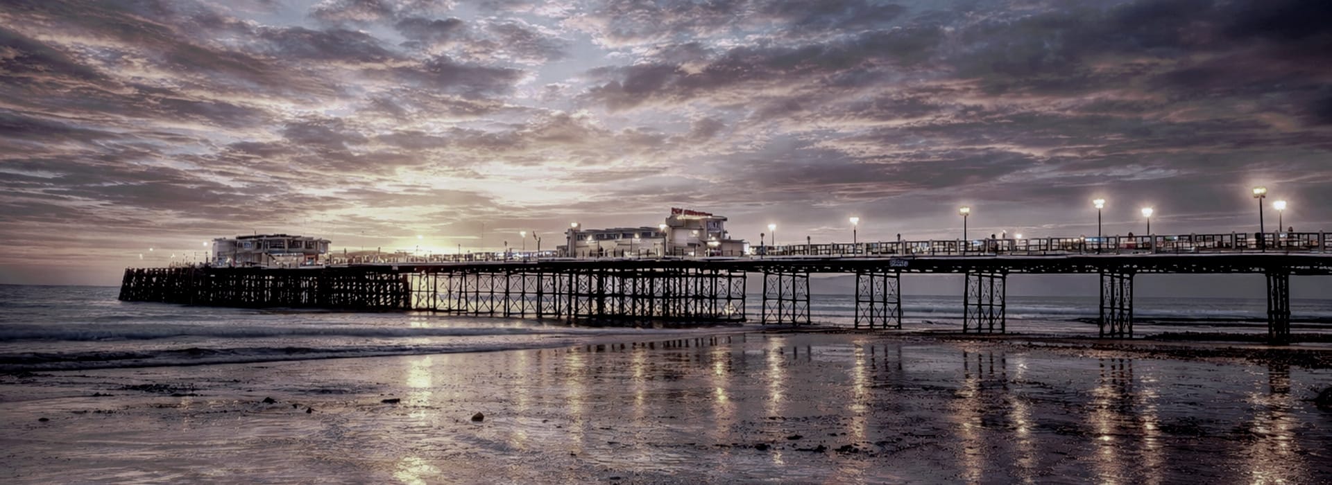 pier stretching over water at dusk with dramatic purple and grey clouds