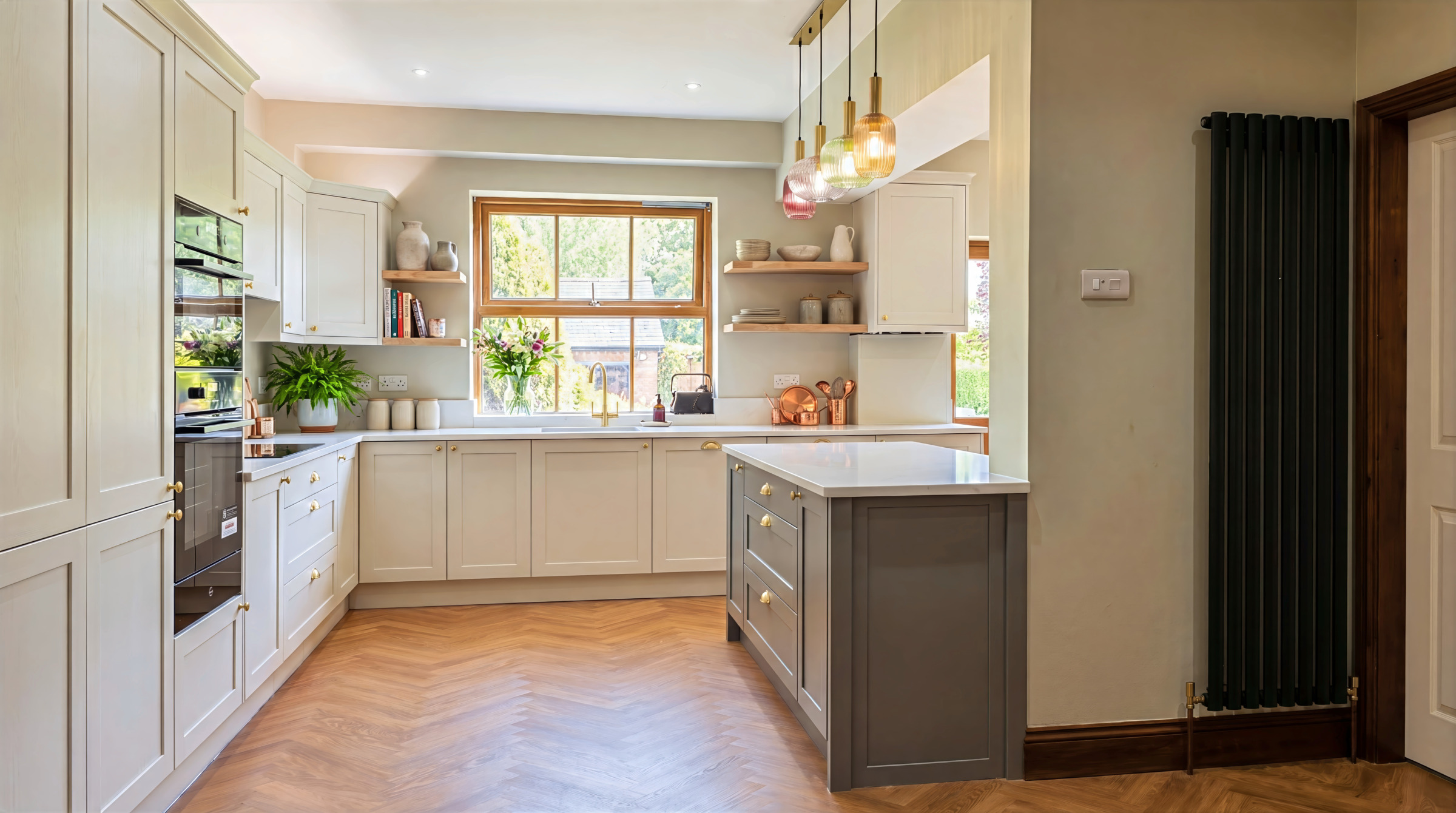 L-shaped shaker kitchen with light green cabinets, a grey island, and herringbone wood-effect flooring